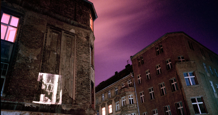 Picture of building in
            Berlin 1991 with projection of Nazy germany by artist Shimon
            Attie